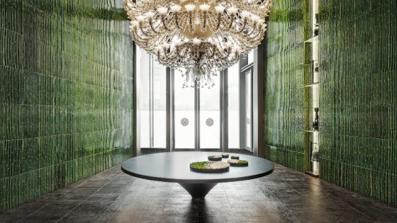 Large chandelier in front of green wall surfaces in lobby