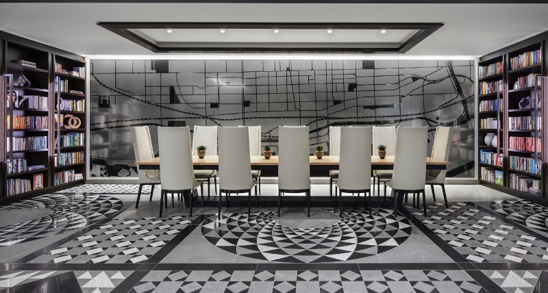 A sharp, dynamic library in Hotel X. The space features monochrome tiles and colourful bookshelf
