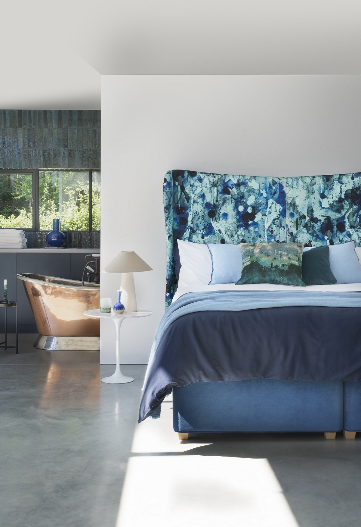 blue hypnos bed in front of copper bath in ensuite bathroom