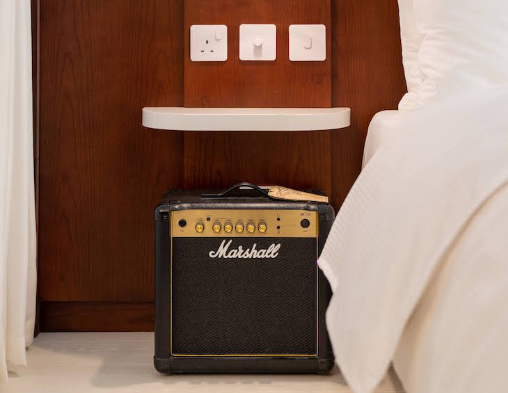 Amp by the side of white bed