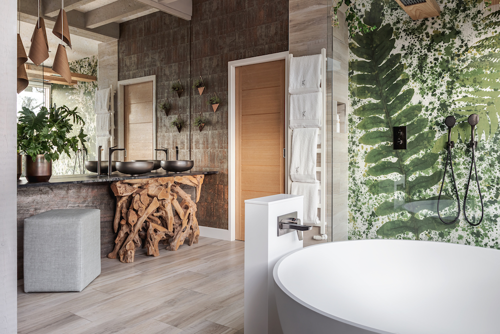 A leafy wallpaper and basin made of wood in the bathoom