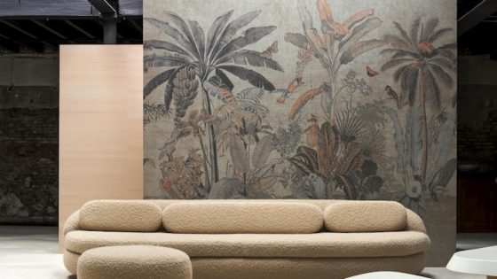 A wallcovering of palm trees infront of modern sofa and warehouse setting