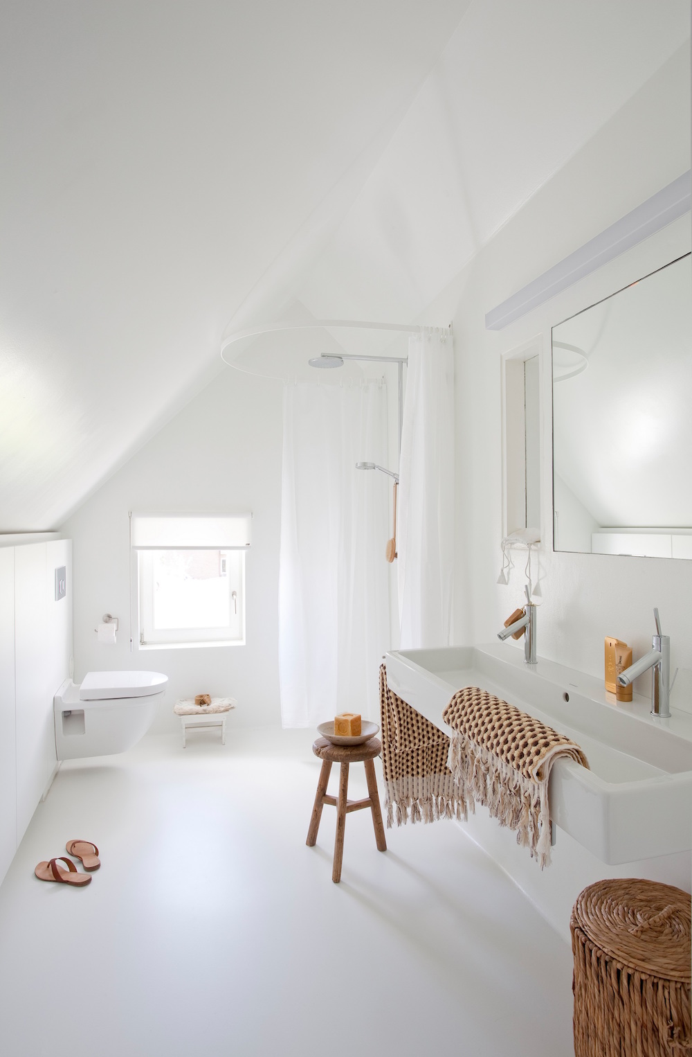 Image caption: Walls, floor, and ceiling, all consistently finished in white, blend with natural materials to create a pleasant ambience - with the large Vero double washbasin and Starck 3 toilet. | Image credit: Duravit
