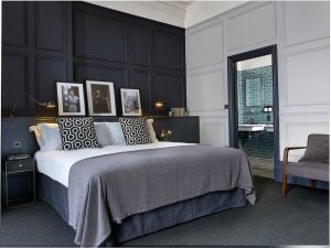 luxury hotel bedroom in shades of grey with bold patterned cushions