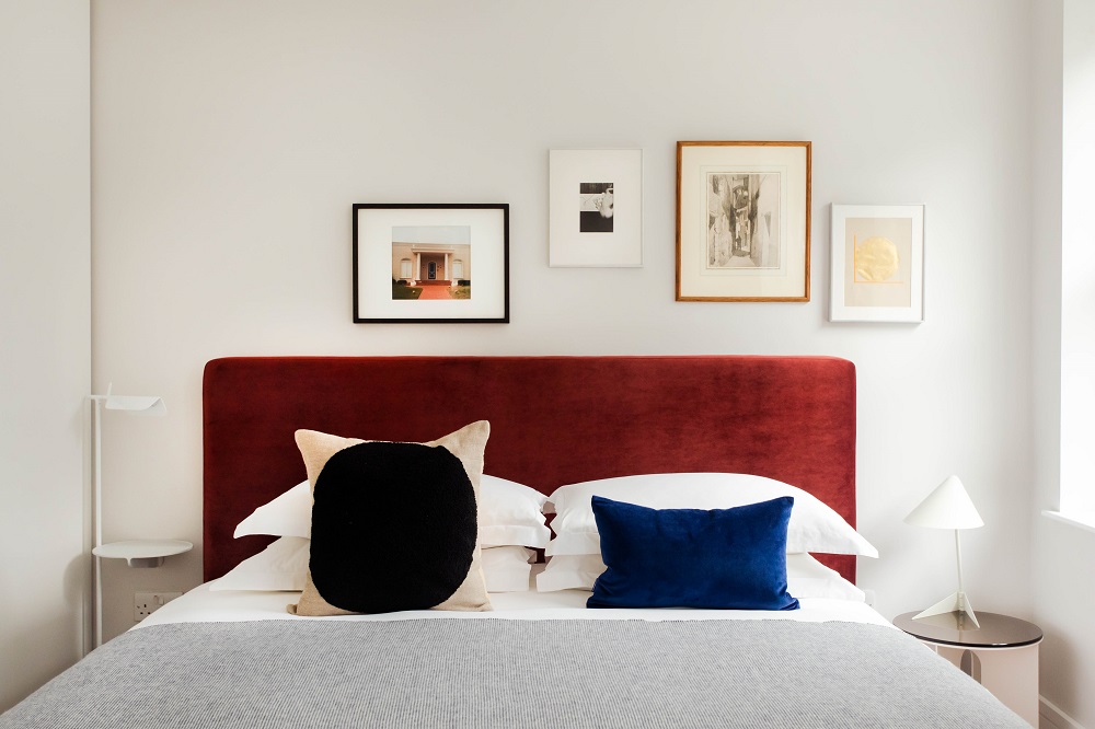 bedroom with red padded headboard and blue accents in the living rooms marylebone collection