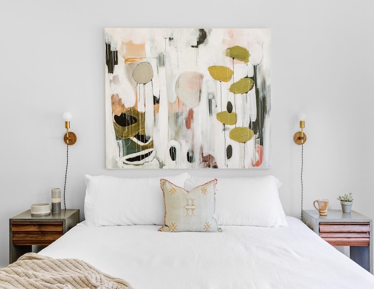 abstract painting in pinks and greens above hotel bed