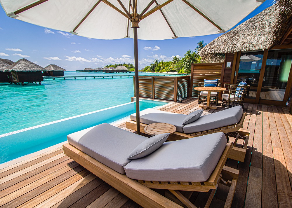 wooden deck and white parasols overlooking the pool and the sea at conrad maldives