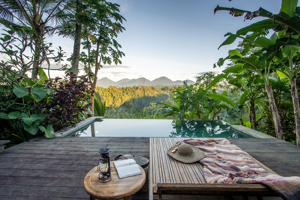 wooden sundeck and an infinity pool with views over the jungle at a Banyan Tree escape