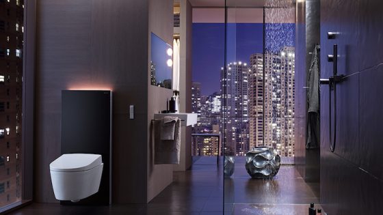 A modern bathroom with shower and glass screens overlooking skyline of city at night
