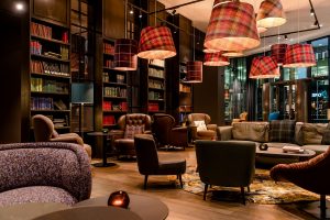 Comfortable lounge area with books and cocktails at Motel One Manchester