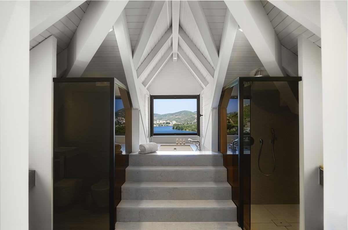 A bathroom inside a suite in Six Senses Douro Valley that has a window overlooking vineyards