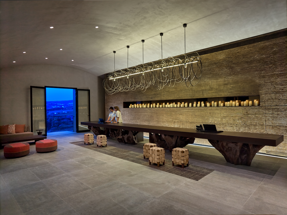 The earthy lobby at Six Senses Douro Valley, featuring a long check-in desk and balcony overlooking the river