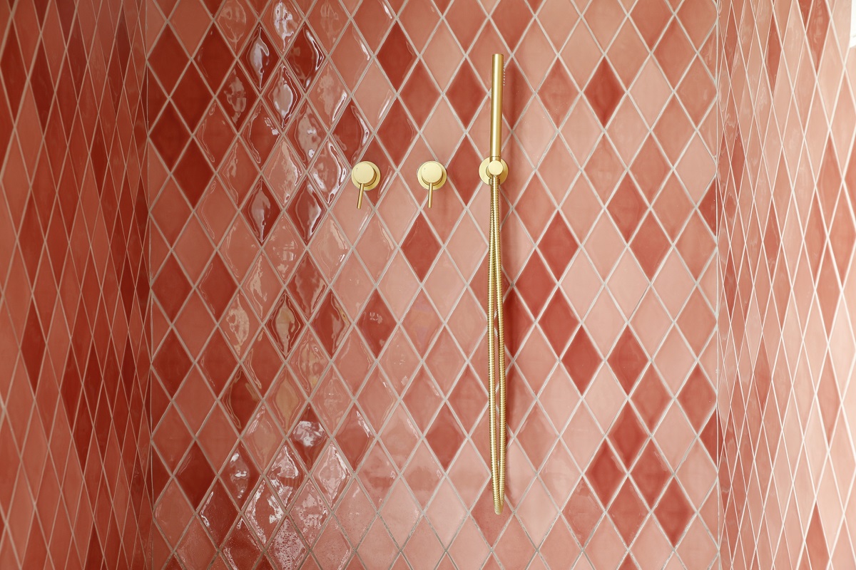 pink tiled shower with brass fittings