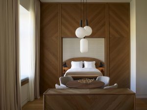 warm tones of wood contrast with crisp white linen in the guestroom at xenodocheiou Milos