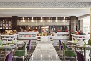 green and purple chairs in the open plan dining experience at Pullman Doha West Bay
