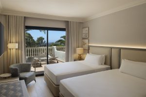 guestroom decorated in grey and white with private balcony at Hilton Mallorca Galatzo