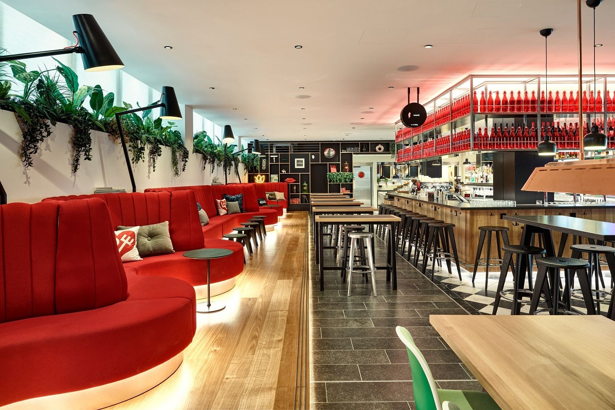 the statement wavy red couch connects spaces in citizenM victoria, along with feature red bottles in the bar