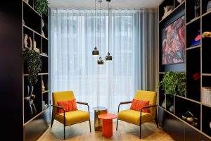 bright yellow chairs, books and art on the walls at citizenM London victoria station