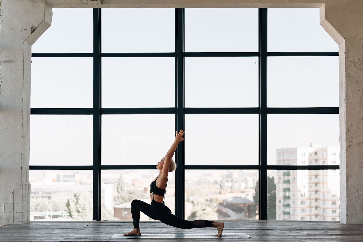 Woman doing yoga in large building with panelled windows