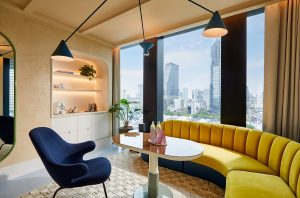 view from the balcony suite over Bangkok in The Standard Bangkok Mahanakhon with yellow couch framing the window and contrasting blues