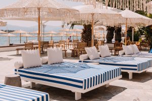 Chaises longues à rayures bleues et blanches avec parasols autour de la piscine de Brown Beach Eretria