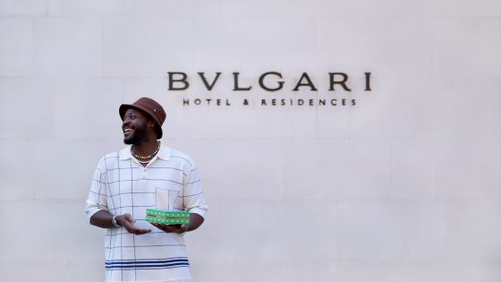 artist Yinka Ilori outside the Bulgari hotel in London holding napkins designed for afternoon tea collaboration