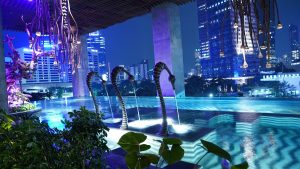 rooftop pool lit up at night looking over Jakarta at The Orient