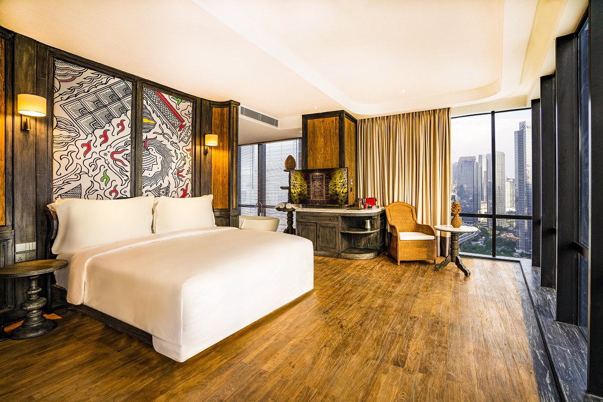 wooden floors and city views in guestroom at The Orient Jakarta with headboard detail from local craft