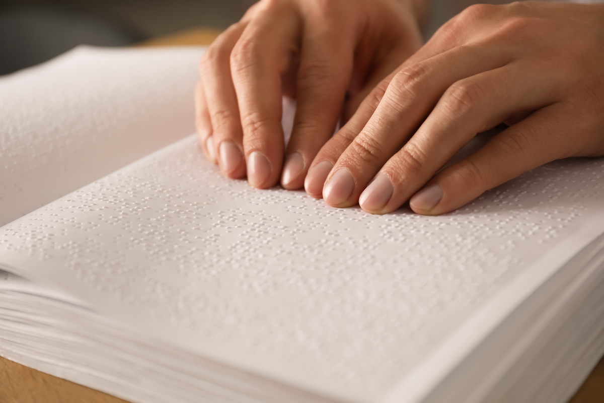 Blind man reading book written in Braille, closeup