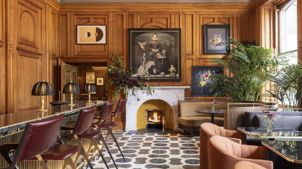 wood panelling and oil paintings above the fireplace in the commons club bar in Virgin Hotels Edinburgh