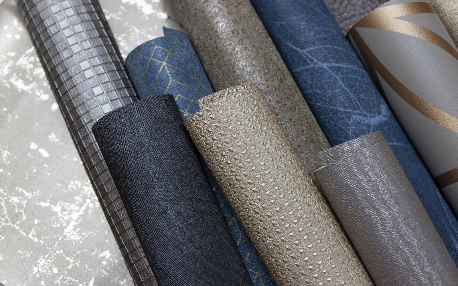 rolls of wallcoverings in blues and metallics from Newmor