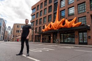 designer Jack Irving stands in front of Mondrian Shoreditch with inflatable sculpture on facade