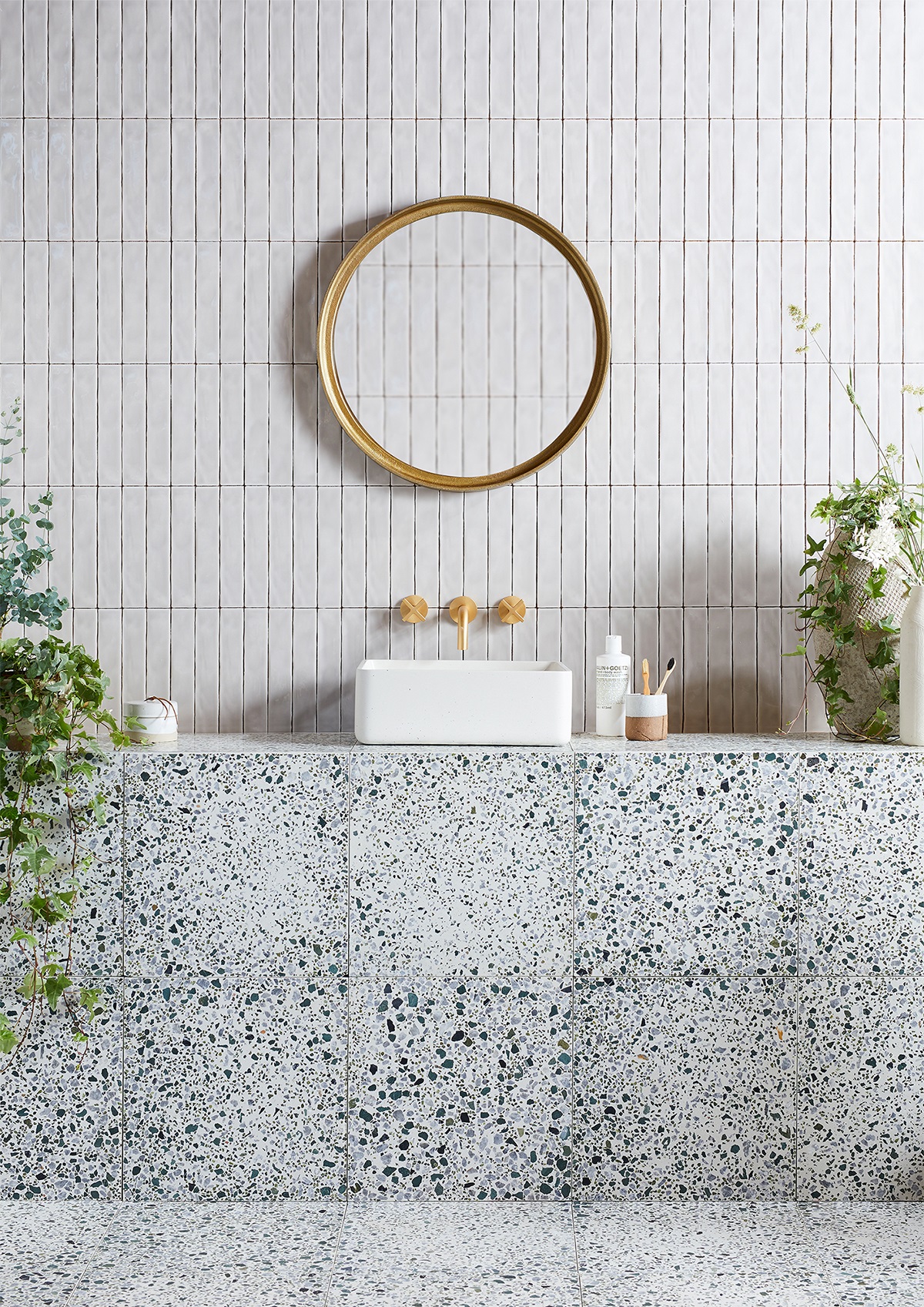 Bert & May fennel terrazzo tiles from Hyperion tiles on the wall in bathroom with round gold framed mirror