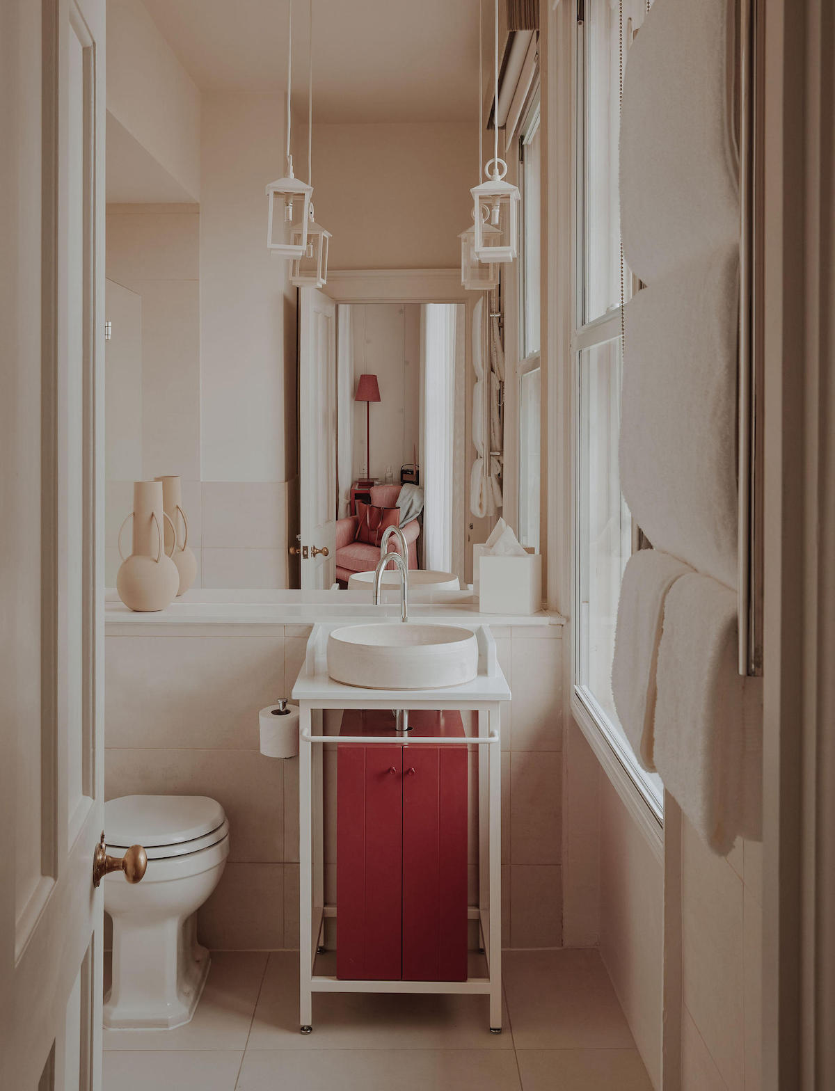 A boutique bathroom, with matte red furniture and hanging pendants