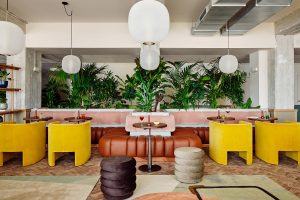 earth tones contrast with bright yello chairs and greenery in Mural Framhouse in WunderLocke in Munich by Locke hotels