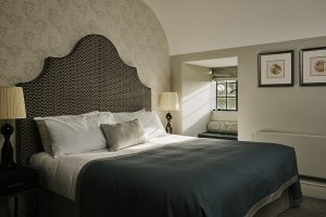 guestroom at Horwood House hotel decorated in shades of grey by Ica with padded oversized headboard and patterned wallpaper