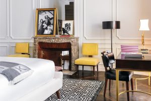 marble fireplace and contemporary design with yellow chair in guestroom at J.K. Place Paris