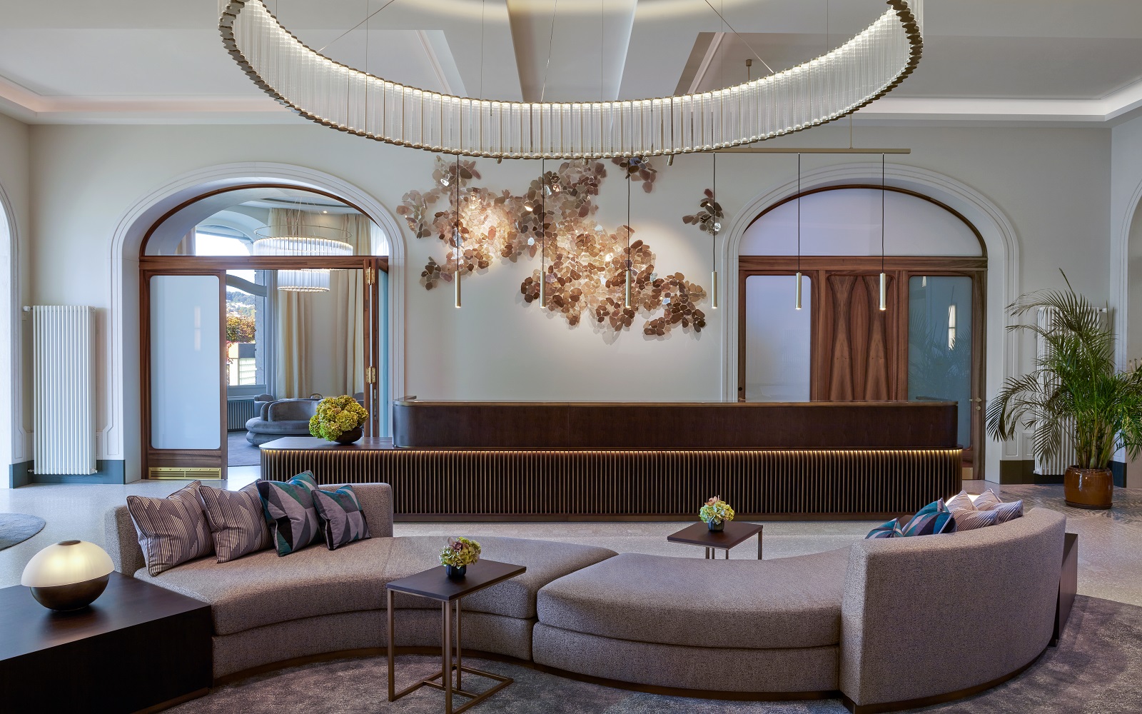 S shaped lavender sofa with statement overhead circualr lighting feature in the lobby of Mandarin Oriental Palace Luzern with interiors by Jestico + Whiles