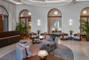 lobby and reception at Mandarin Oriental Luzern with timber-lined arched doorways, curved sculptural seating, walnut joinery, and terrazzo flooring
