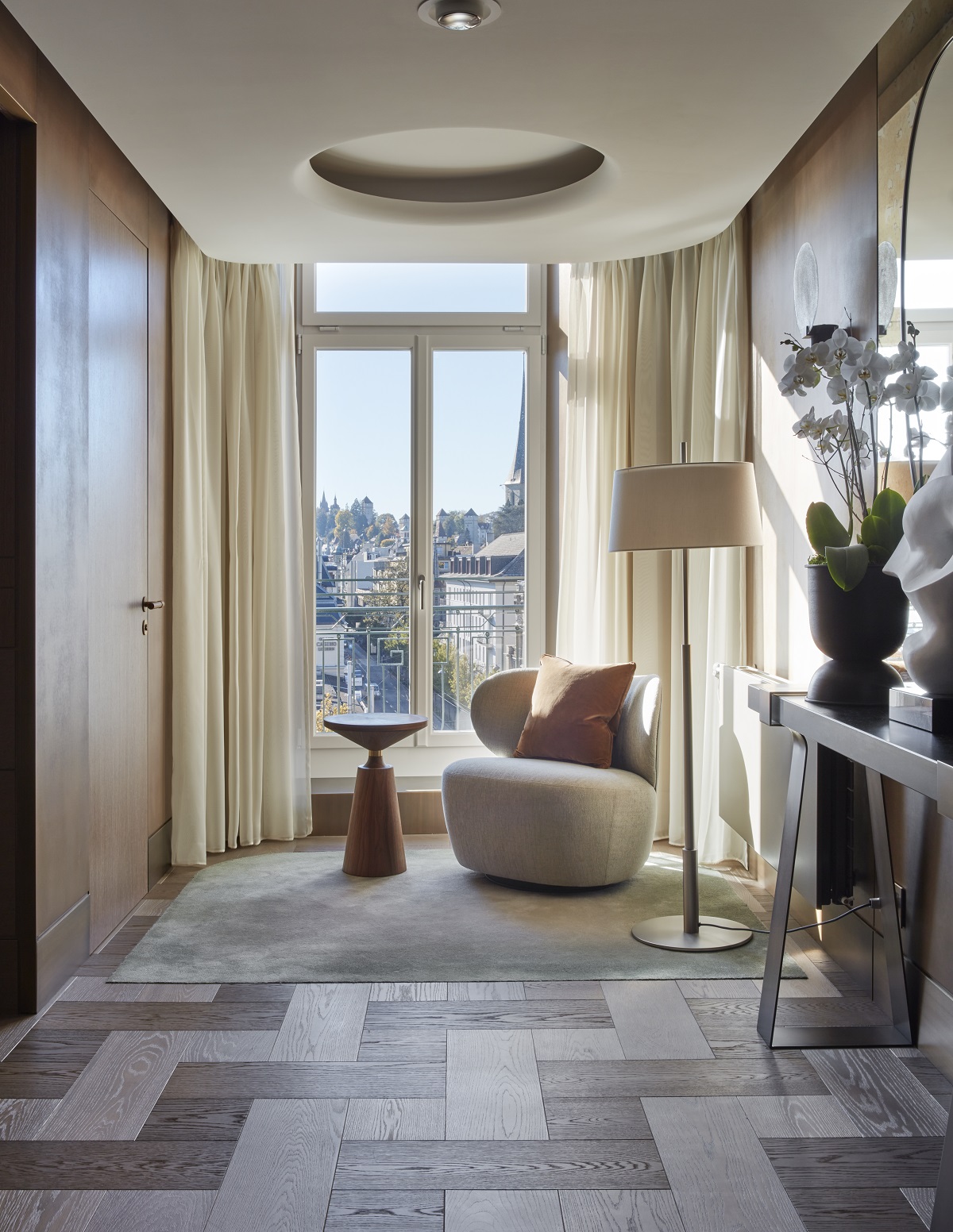 rounded chair and table with bespoke light in window with repeating circle design in guestroom of Mandarin Oriental Luzern