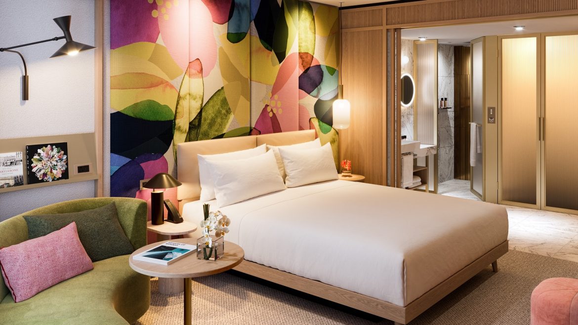 The BoTree guestroom with colourful abstract pattern behind bed
