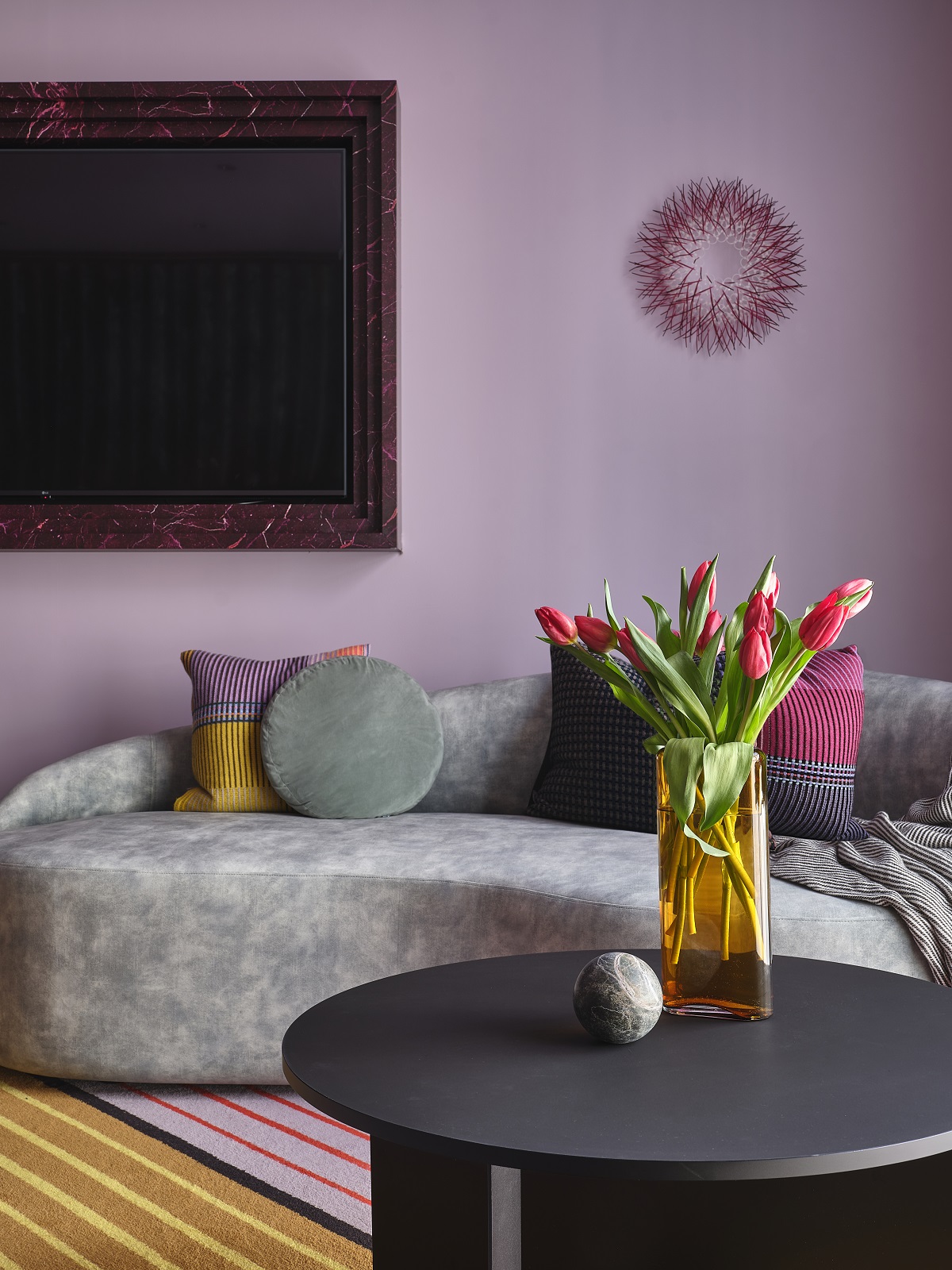 lilac walls and grey sofa with sea urchin sculpture on the wall at Naumi Wellington
