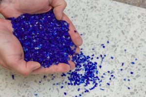 a hand full of recycled blue glass chips used to make TREND surfaces