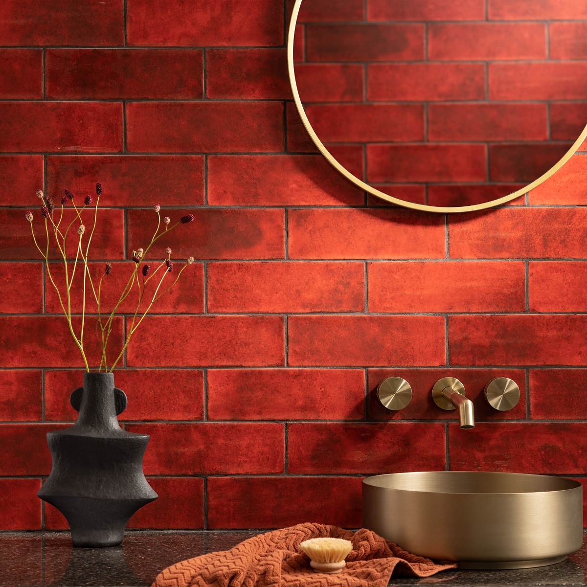 Titan red tiles from CTD Tiles behind brass bathroom fittings and a sculptural vase