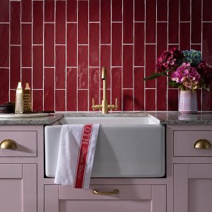 pastel pink kitchen units with brass handles and Poitiers Bordeaux tiles from CTD Tiles on the wall