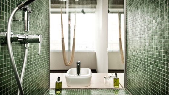 view from bathroom with green mosaic tiles by TREND Group across to room with hammock