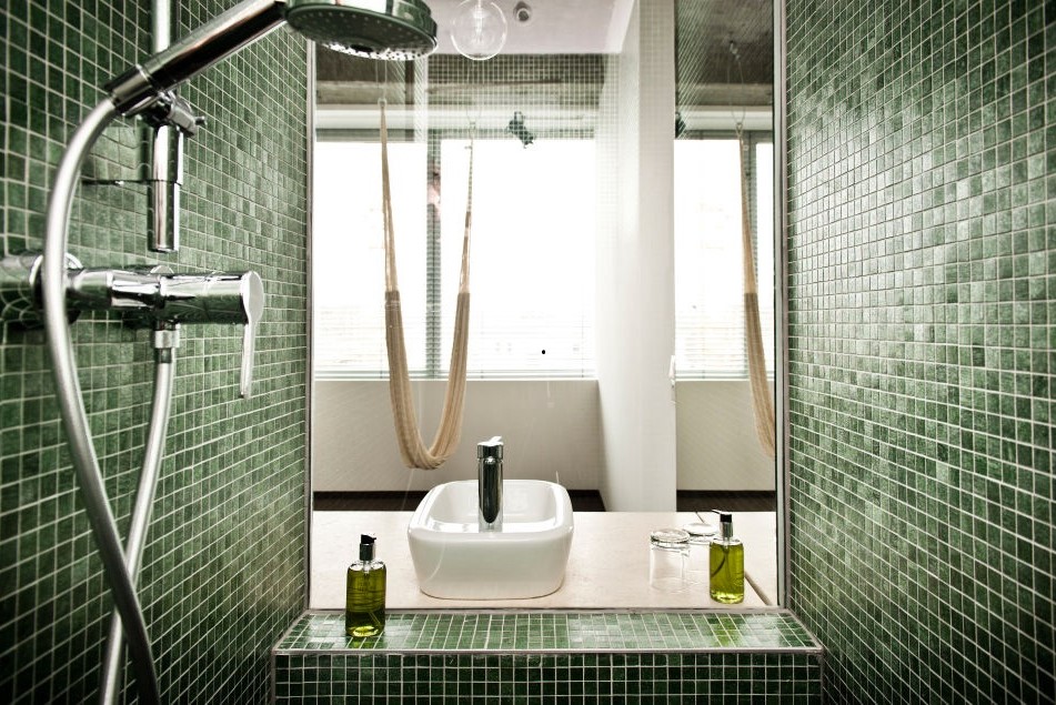 view from bathroom with green mosaic tiles by TREND Group across to room with hammock