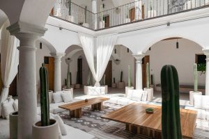 white arches and period columns with pots of cacti and white curtains in the courtyard at Hotel sin Nombre