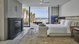 double bed in front of the fireplace with doors open onto the beach at Four Seasons costa Palmas