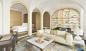 gold arches a white sofa and blue and gold carpet in the suite at Raffles Doha